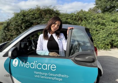 Teamleiterin Sadaf Aminpour vom Medicare Team Neuallermöhe mit einem Medicare-Pflegefahrzeug in Hamburg