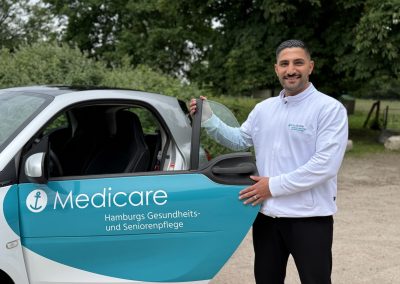 Teamleiter Farhad Ramazani vom Medicare Team Wilhelmsburg mit einem Medicare-Pflegefahrzeug in Hamburg